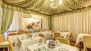 Un espace repas avec des tables dressées pour le repas, des chaises en osier et un lustre.