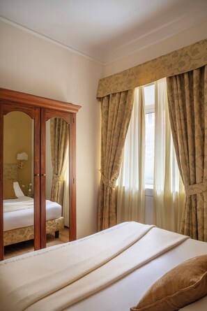 Une chambre d’hôtel avec un lit, une armoire en bois et des rideaux.