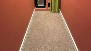 Un couloir étroit doté d’un bureau intégré et d’une étagère, d’un rideau vert et d’un sol recouvert de moquette.
