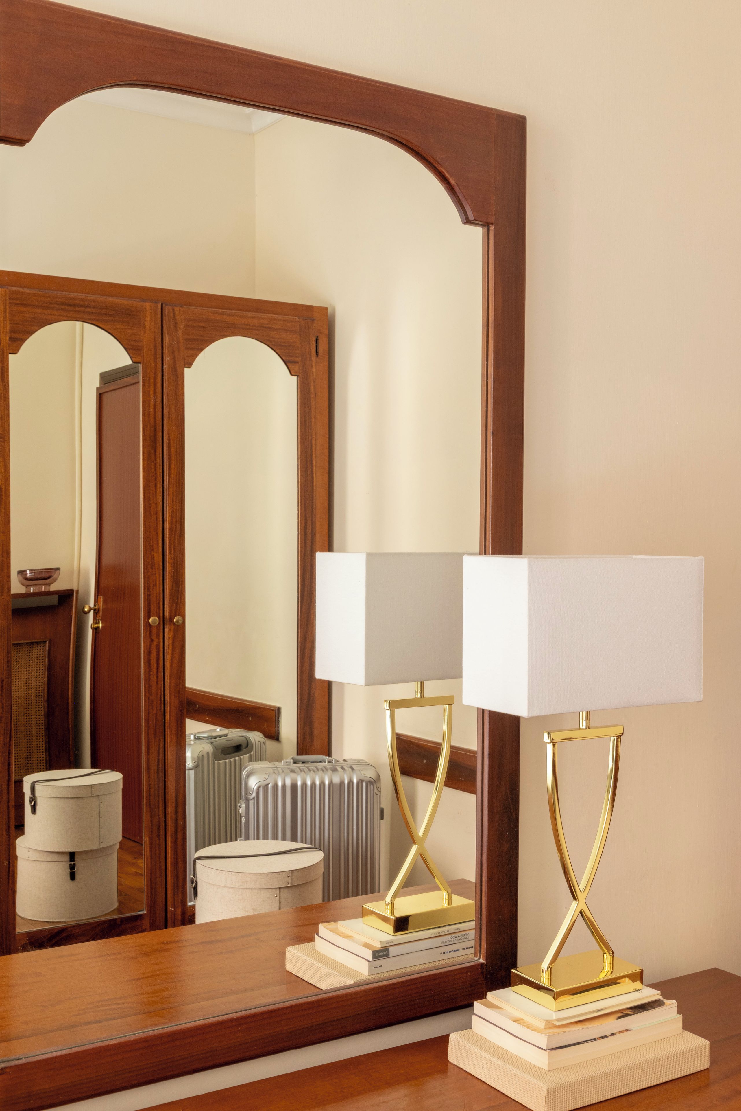 A wooden dresser with a mirror above it, reflecting a room with a door and a radiator.