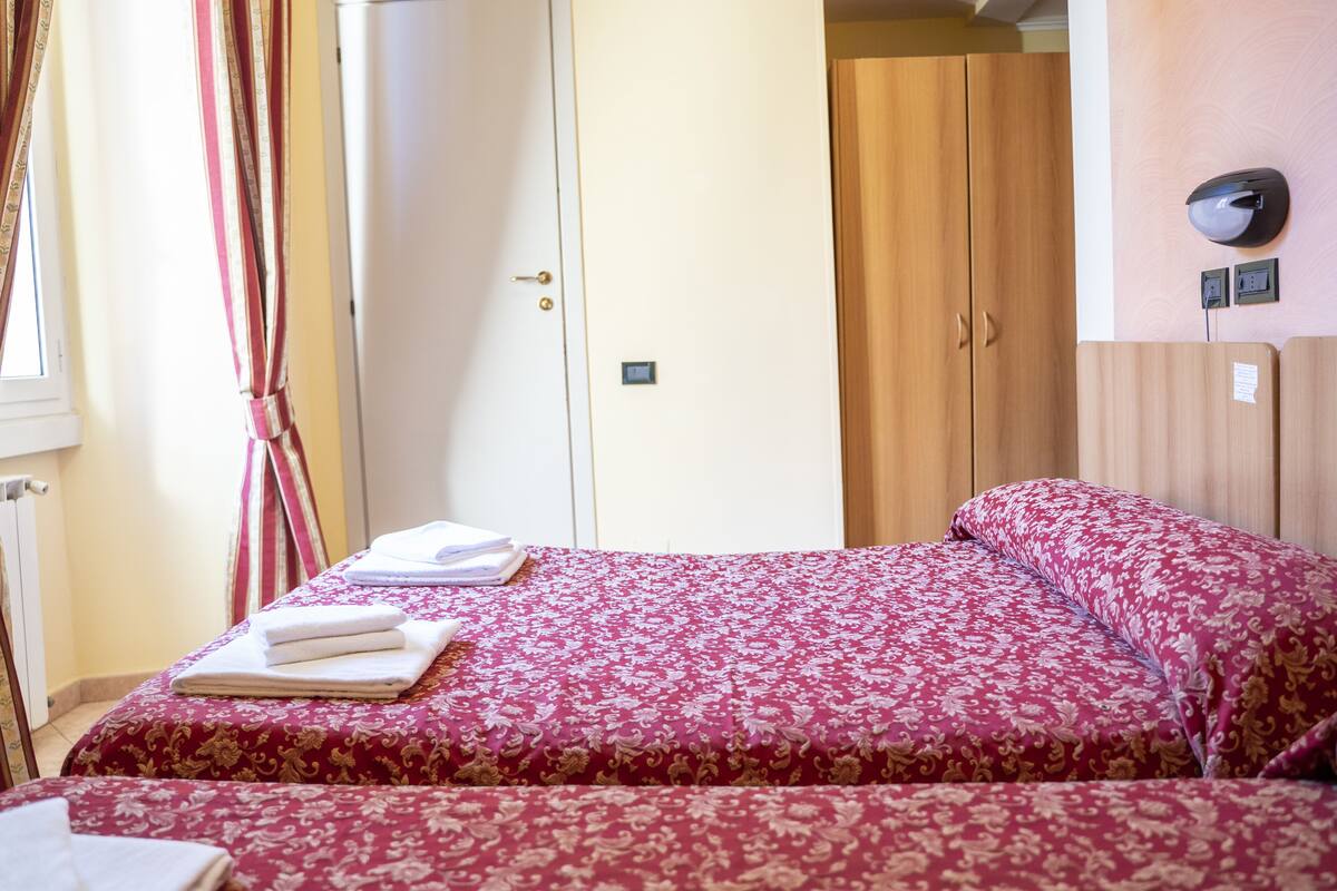 A hotel room with a bed, a wardrobe, and a mirror on the wall.