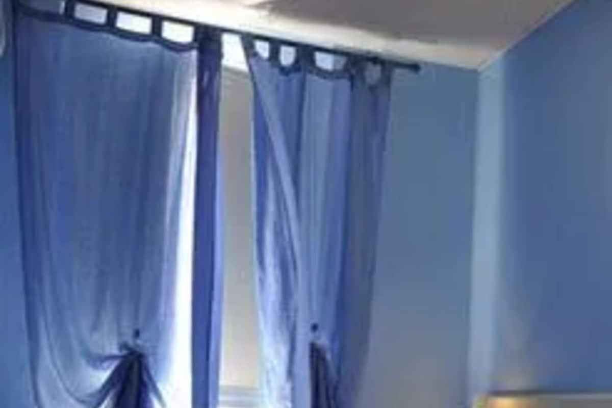 Una habitación de hotel con una cama, una mesita de noche con lámpara y cortinas azules.