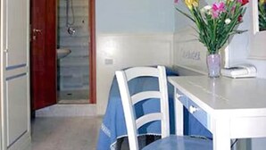 Una cucina con un piano di lavoro bianco, una sedia blu e un vaso con fiori.
