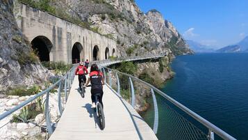 Un sentiero con ciclisti, un ponte e una scogliera rocciosa che si affaccia su un corpo d'acqua.