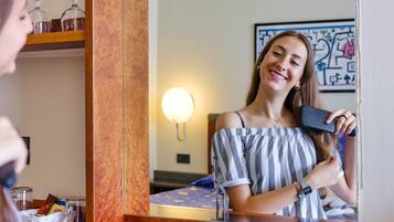 A hotel room with a wooden dresser, a mirror, and a bed with a blue bedspread.