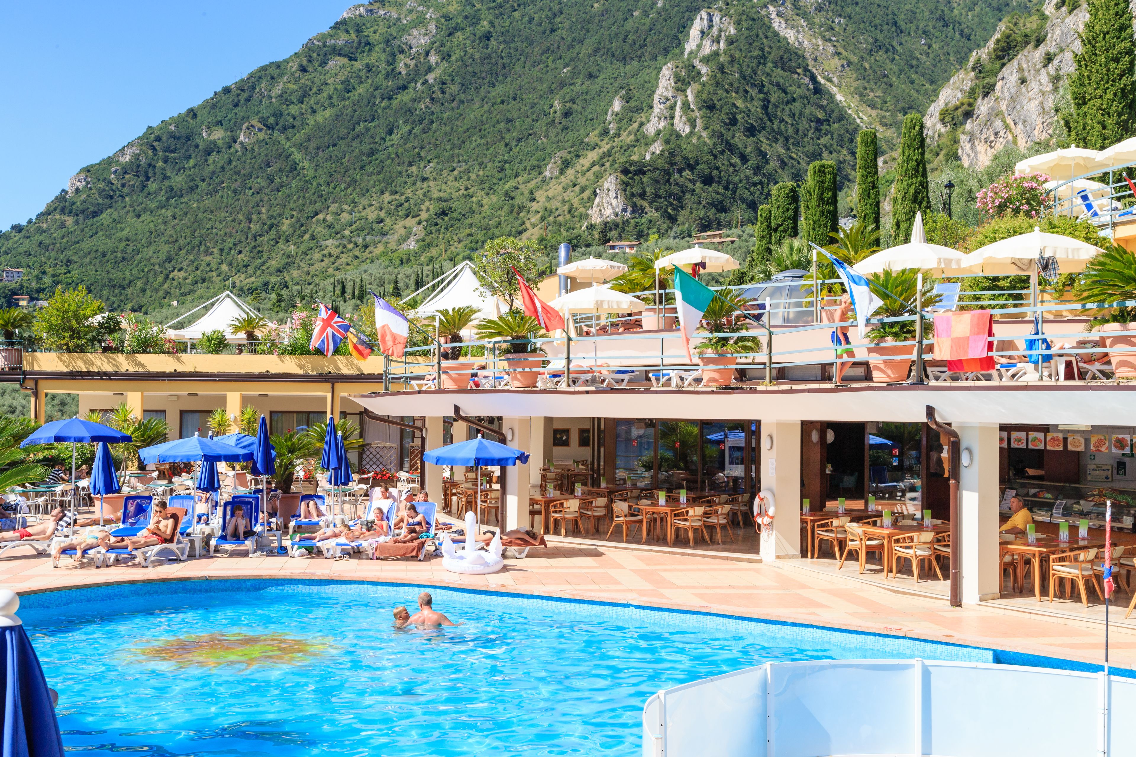 A pool area with lounge chairs and umbrellas, a bar, and a view of mountains.