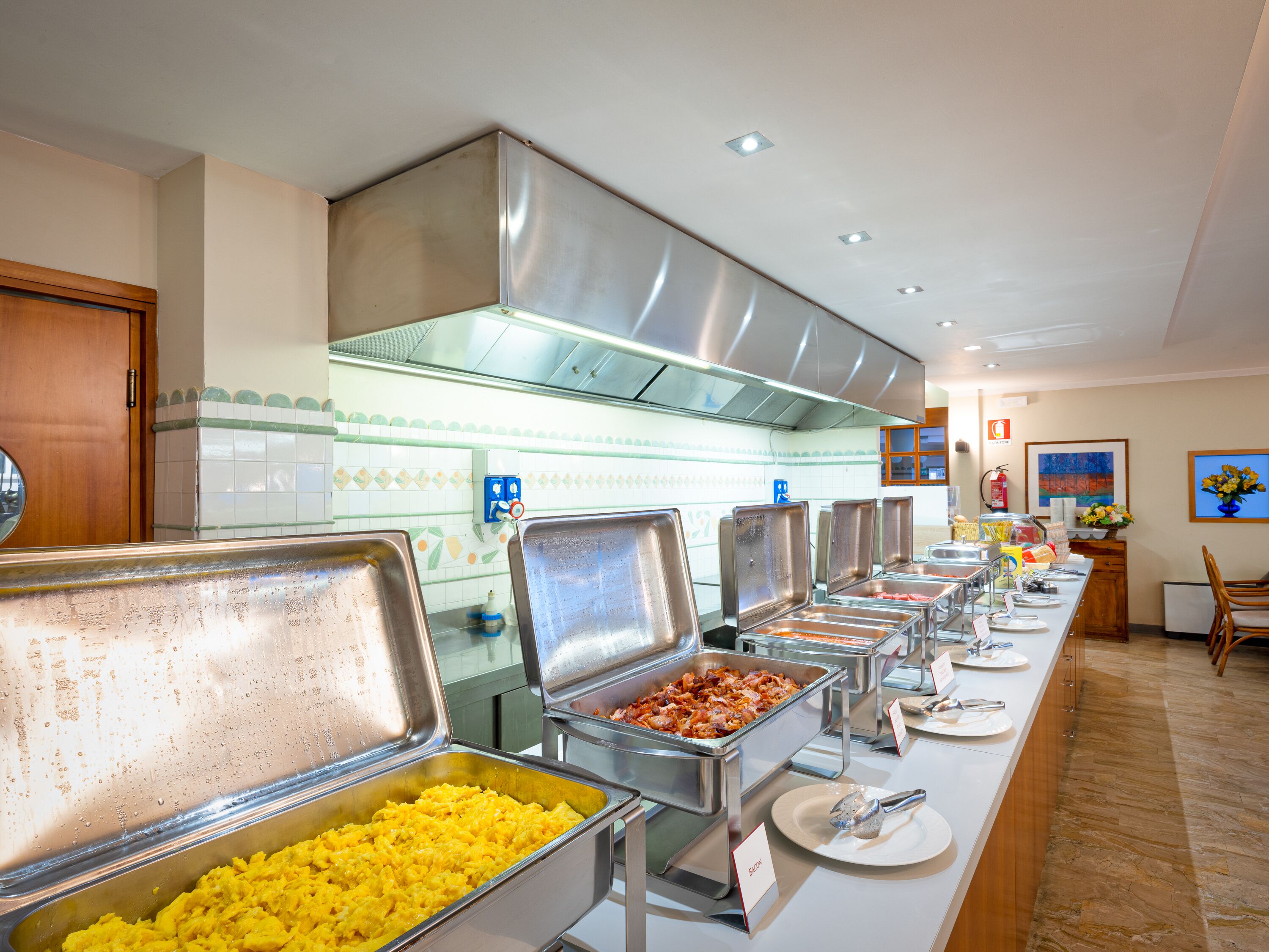 Een buffetgedeelte met diverse food stations, waaronder een hoek voor roerei en een voor spek.