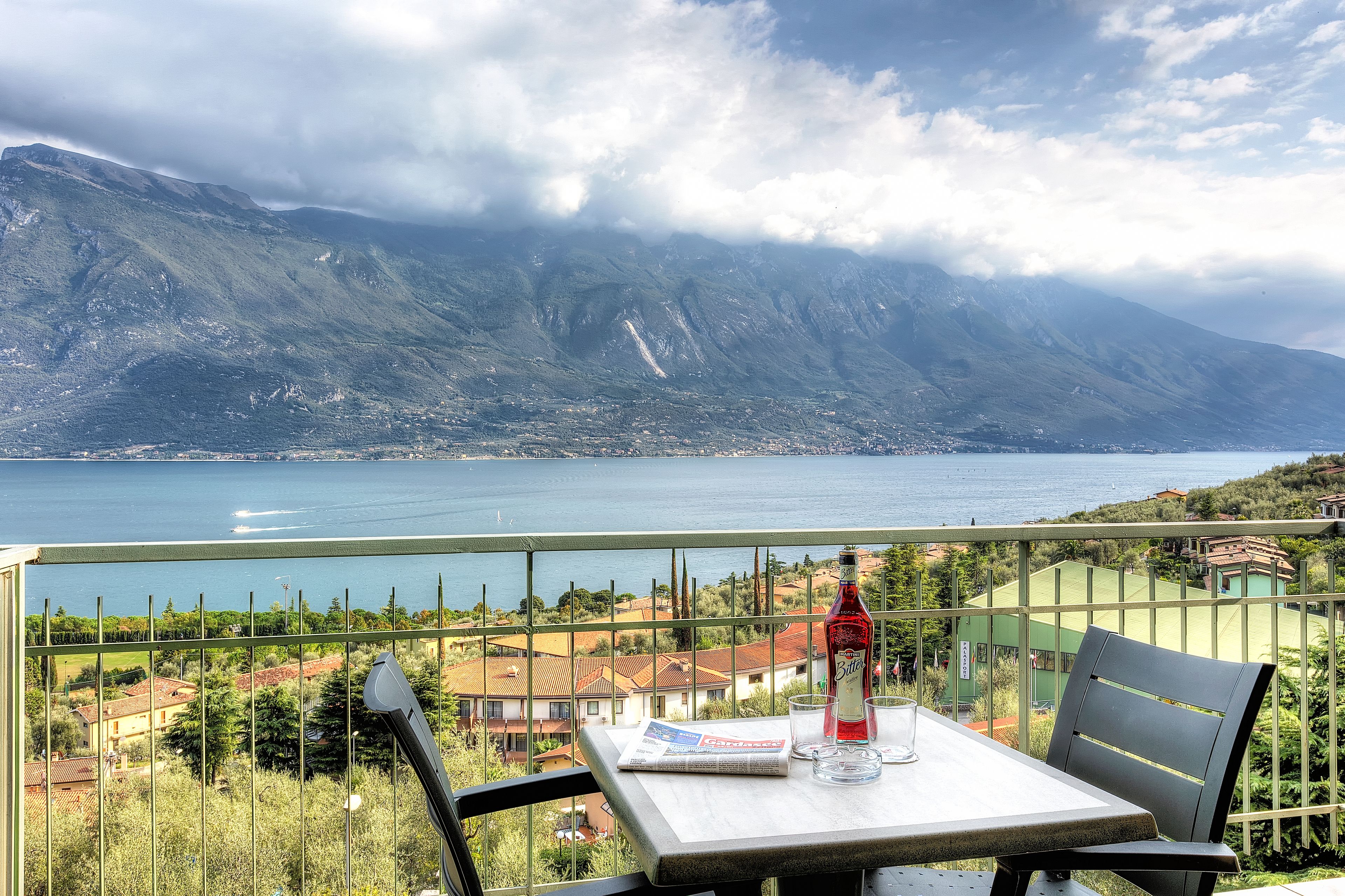 Ein Balkon mit Tisch, Stuhl, Flasche und Glas.