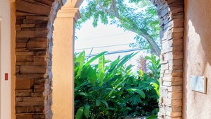 A stone archway leading to a pathway surrounded by lush greenery. - Maui Beach House (Lahaina)