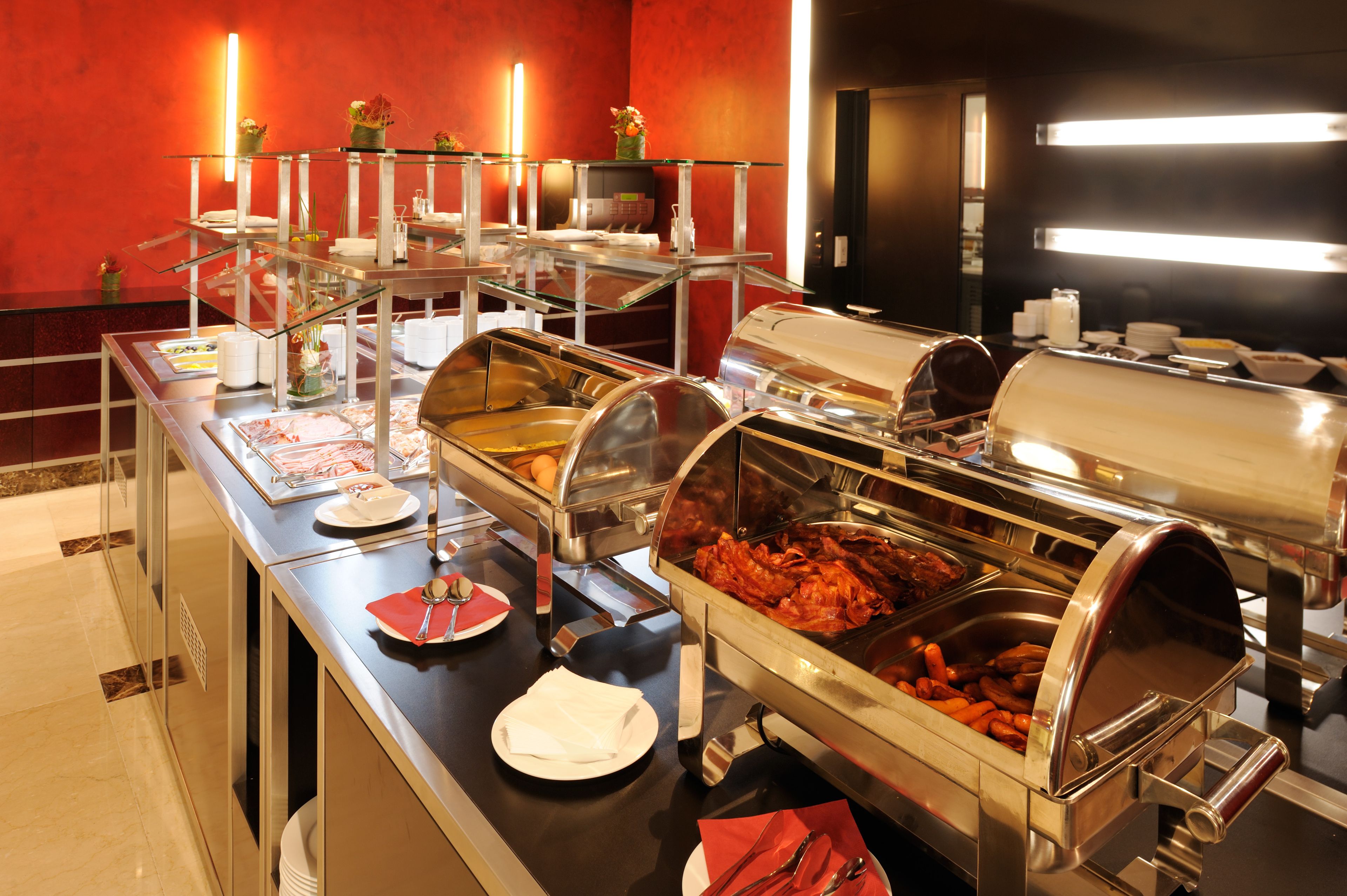 Montaje tipo buffet con múltiples estaciones de comida, incluyendo una parrilla y una variedad de platos.
