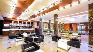 En hotellobby med en bardel, sittplatser och en receptionsdisk.