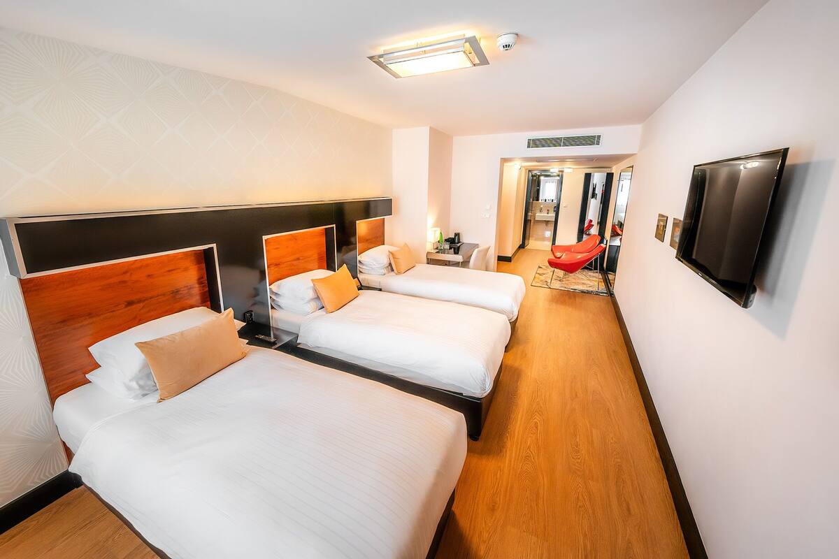 Une chambre d’hôtel avec deux lits, une télévision et un couloir menant à la salle de bain.