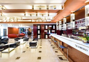 Uma área de bar moderna com estação Nespresso, assentos e uma parede decorativa com painéis estampados.