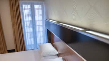 Una habitación de hotel con una cama, una ventana con cortinas y un papel tapiz estampado.
