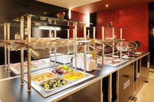 Uma mesa de buffet com várias vitrines de vidro e bandejas de frutas e legumes.