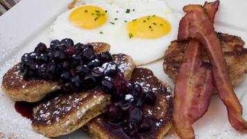 A plate with French toast, two fried eggs, and bacon.