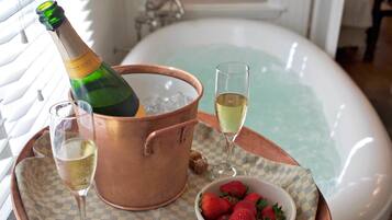 Ein Kupferkübel mit einer Champagnerflasche, zwei Champagnergläsern, einer Schale Erdbeeren und einer Badewanne.