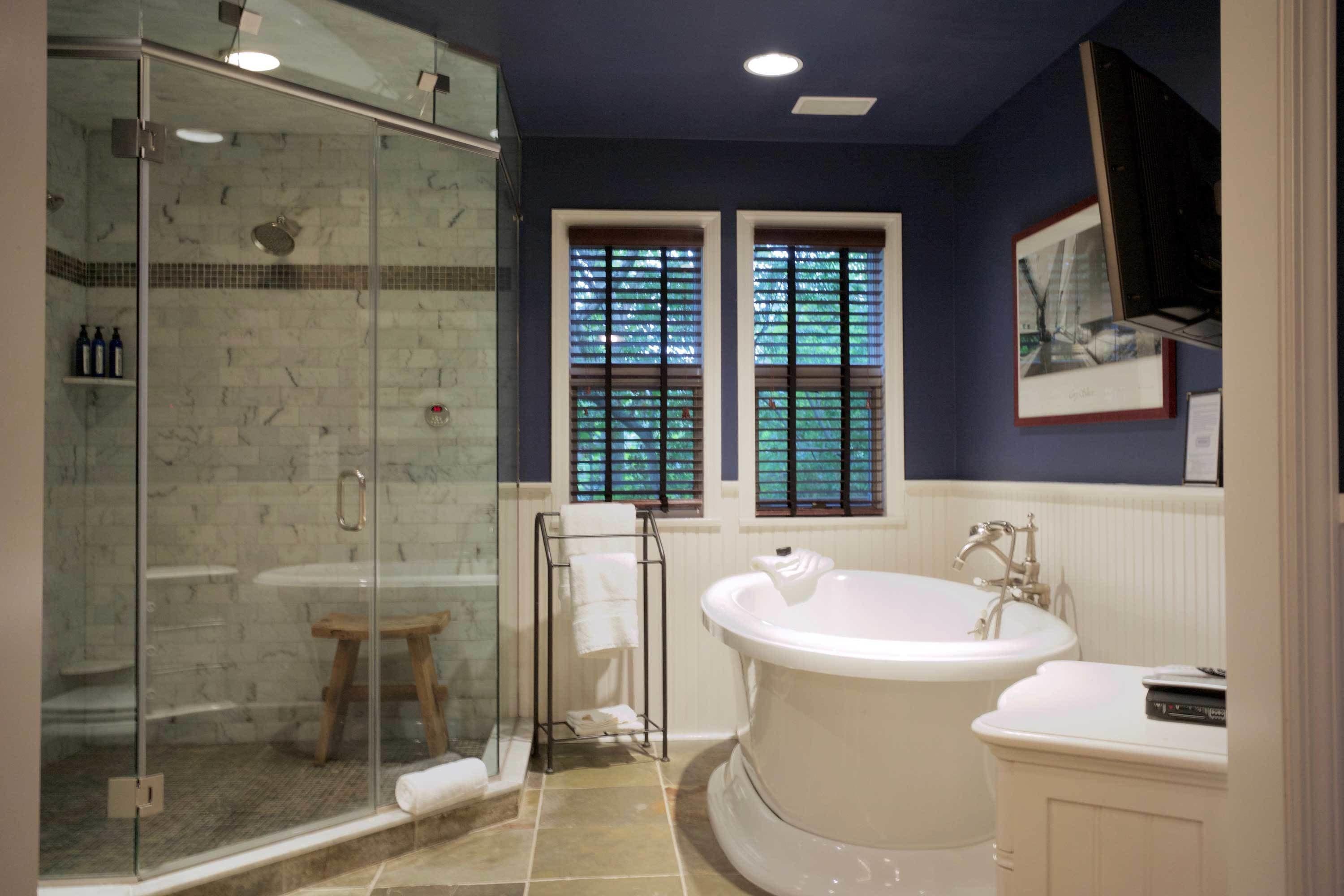 A bathroom with a glass-enclosed shower, a freestanding bathtub, and a vanity with a sink.