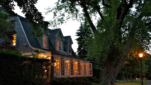 A house with a sloped roof, large windows, and a pathway leading to the entrance. - Mill House Inn (East Hampton)