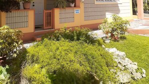 A two-story building with a covered entrance, potted plants, and a sign indicating a stairway. - Greenhaven Cottage B&B (Les Coteaux)