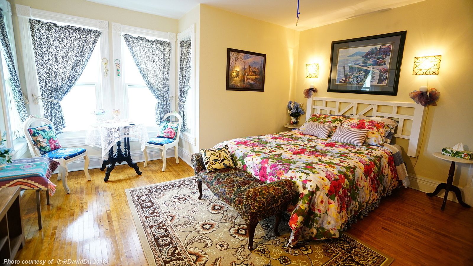 A cozy bedroom with a floral bedspread, a wooden floor, a small rug, and a decorative animal statue.