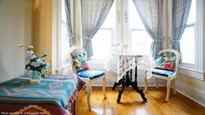 A room with two chairs, a small table, and a window with patterned curtains. - Niagara Inn Bed & Breakfast (Niagara Falls)