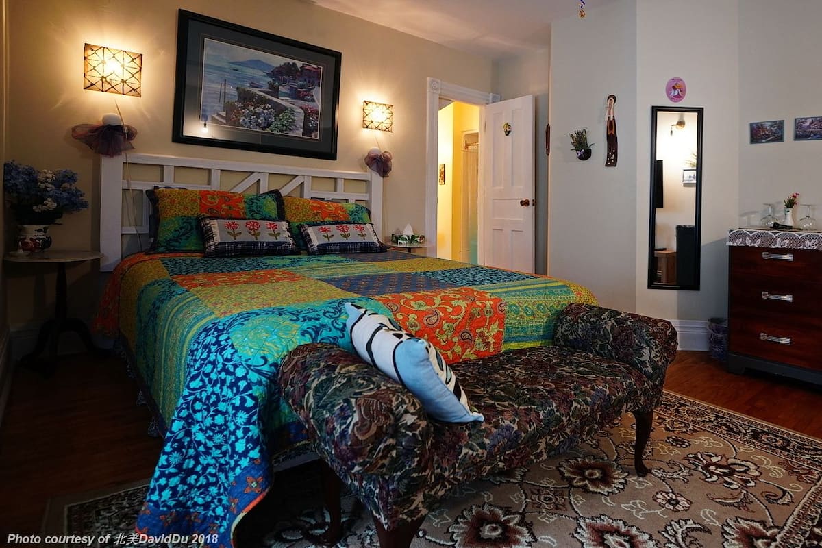 A bedroom with a bed, a chair, a dresser, and a rug.