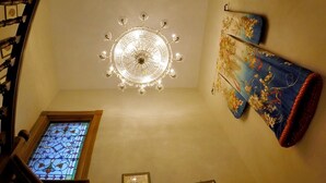 A staircase with a wooden handrail, a chandelier, a stained glass window, and a framed picture on the wall. - Niagara Inn Bed & Breakfast (Niagara Falls)