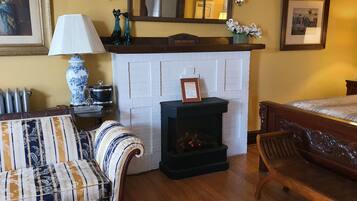 A cozy room with a fireplace, a sofa, a bed, and a table with a lamp.