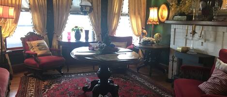 A room with a round table, red chairs, a patterned rug, and a decorative floor lamp.
