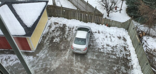 A car parked in a snowy driveway with a wooden fence and a ladder in the background. - A Night to Remember Bed & Breakfast (Niagara Falls)