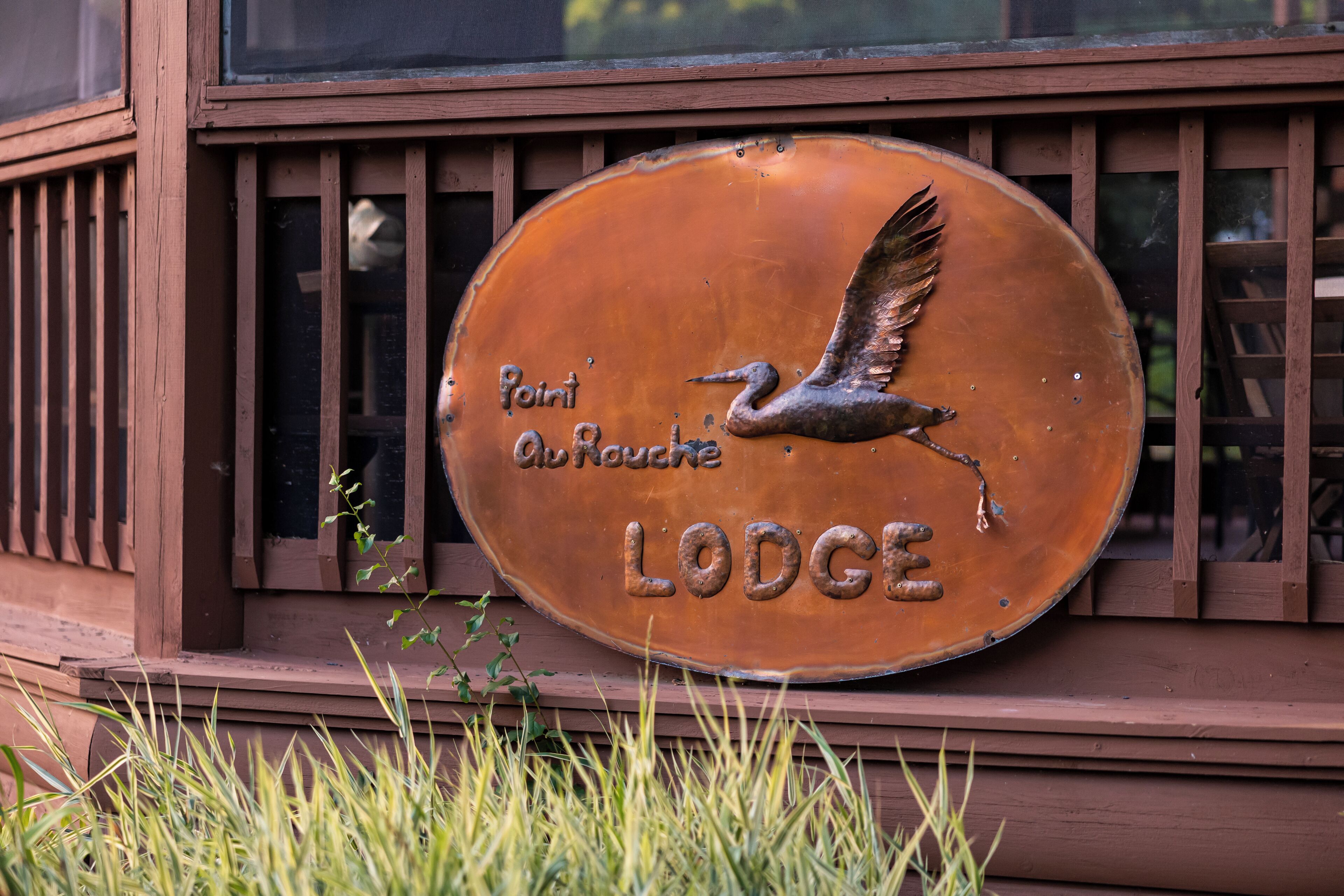 A lodge sign with a bird design and the words "Point Abouache Lodge".