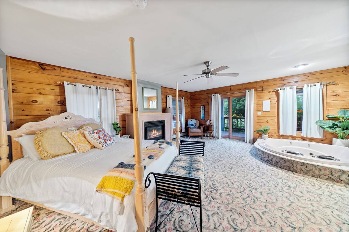 Um quarto espaçoso com uma cama grande, um espaço de estar com lareira e um banheiro separado com banheira.