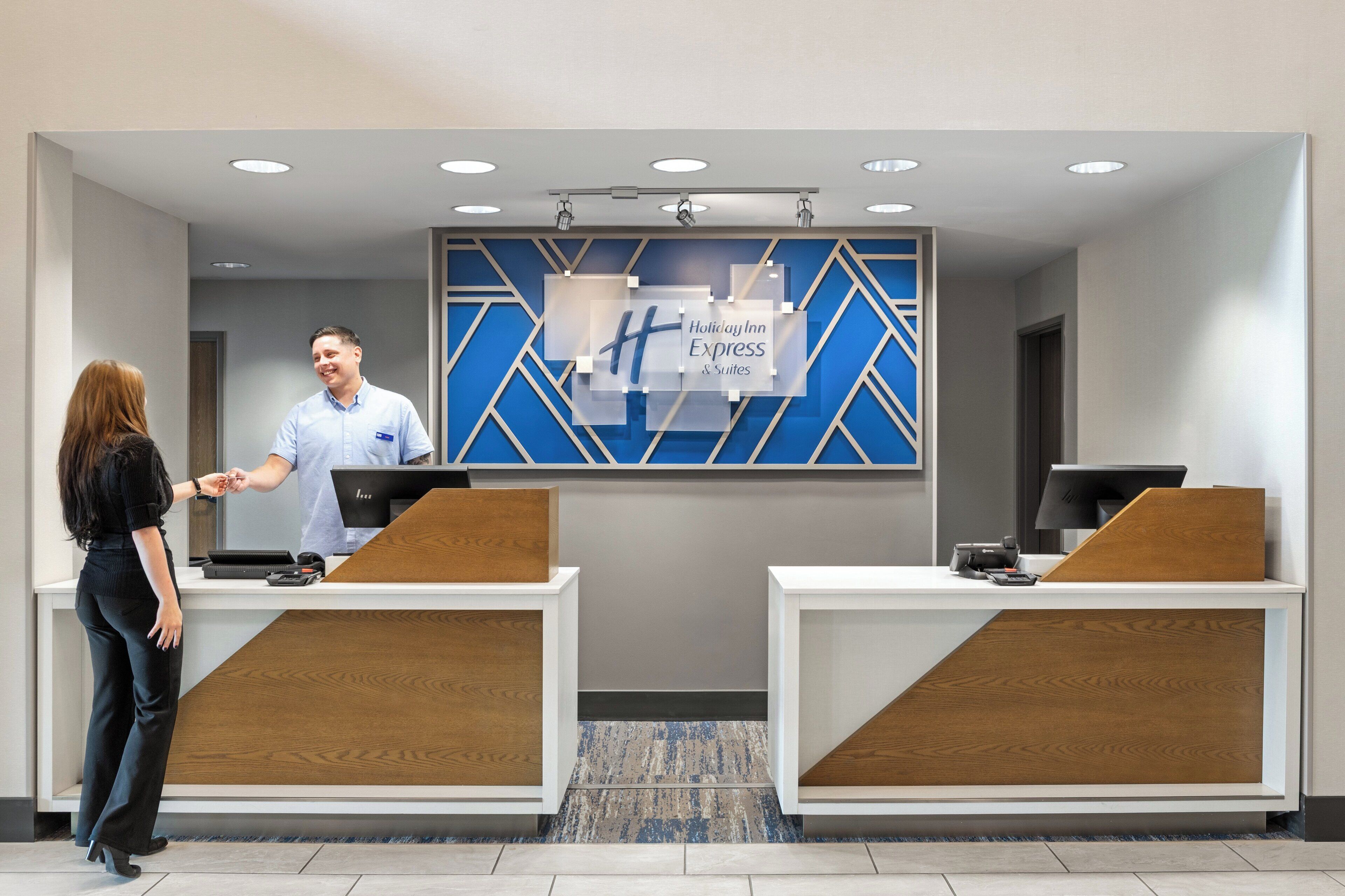 A reception area with two counters, a blue and white wall with the Holiday Inn Express logo, and a modern design.