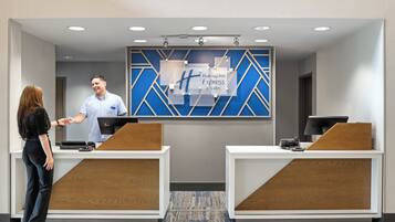 A reception area with two counters, a blue and white wall with the Holiday Inn Express logo, and a modern design.