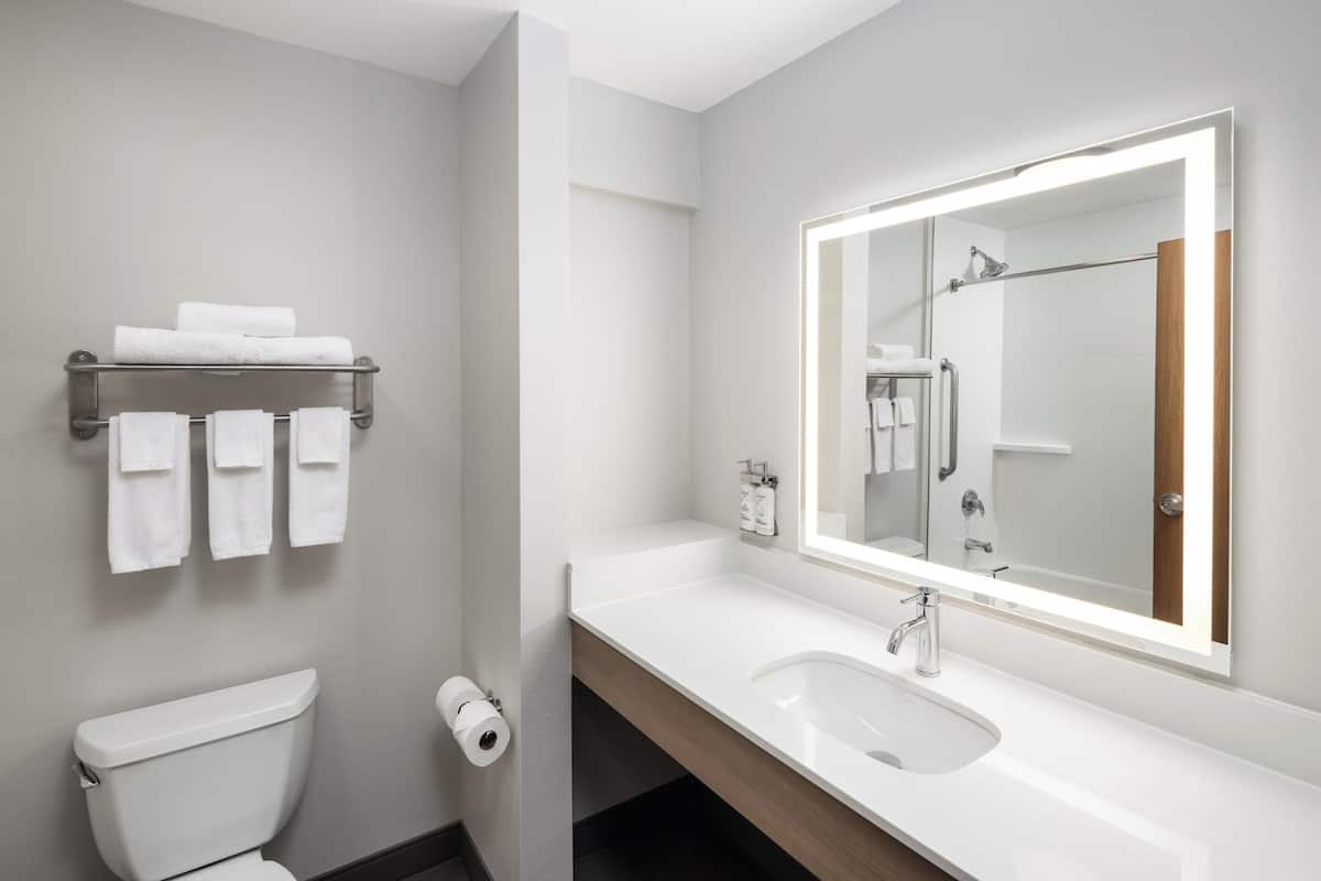 Ein modernes Badezimmer mit einem weißen Waschbecken, einem großen Spiegel und einem Handtuchhalter.