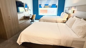 A hotel room with a large bed, a desk, a chair, and a TV.