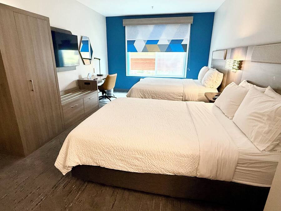 A hotel room with a large bed, a desk, a chair, and a TV.