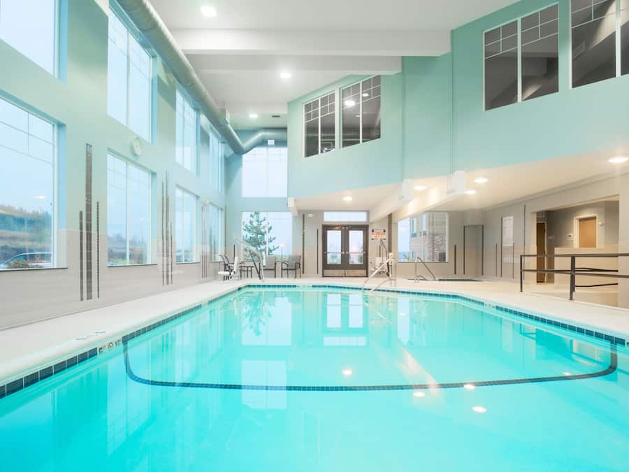 Een binnenzwembad, ligstoelen bij het zwembad