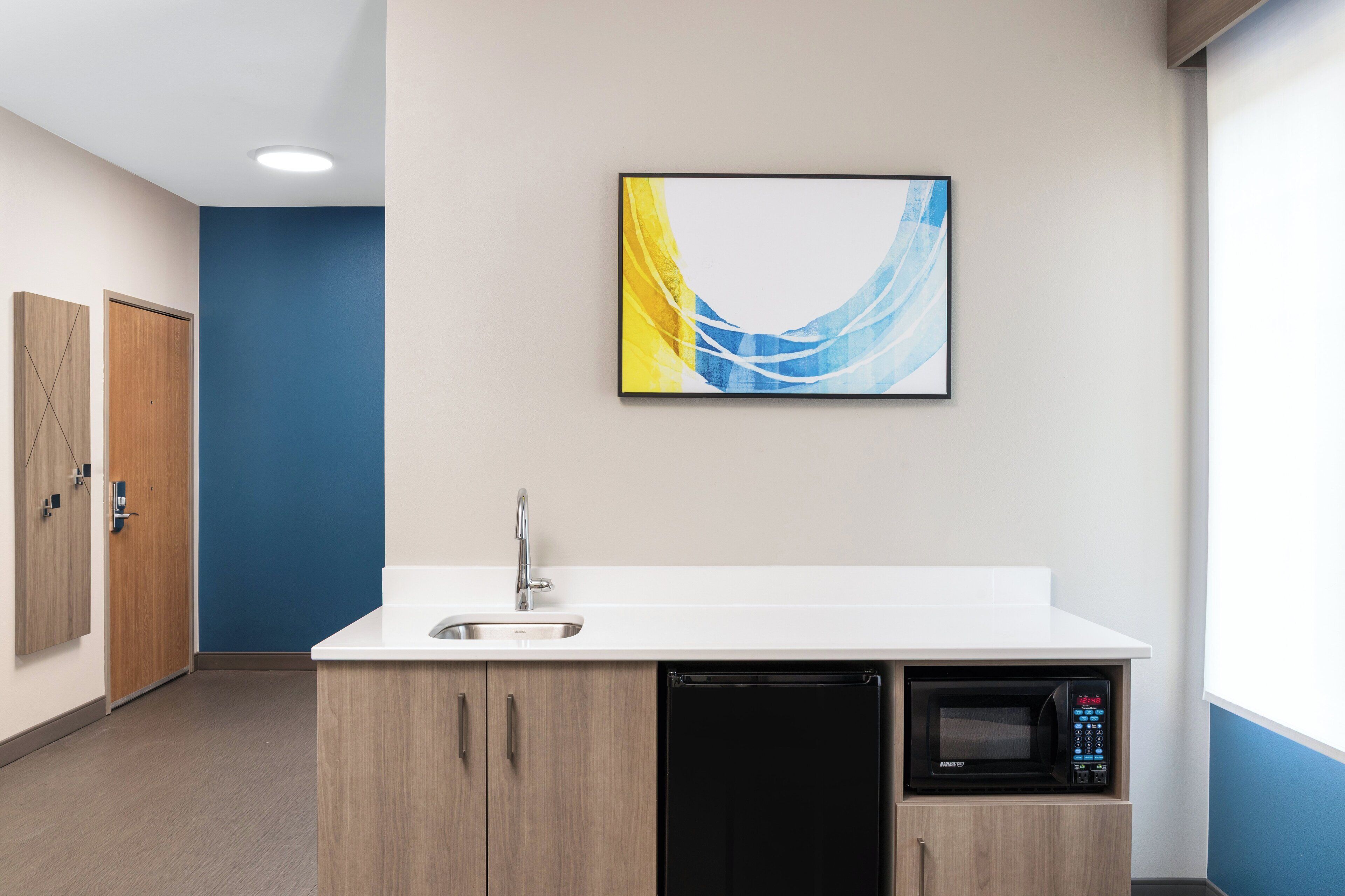 A modern kitchen with a built-in microwave, a sink, and wooden cabinets.