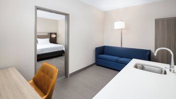 Una habitación de hotel con una cama, un sofá azul, un escritorio con una silla y un lavamanos.