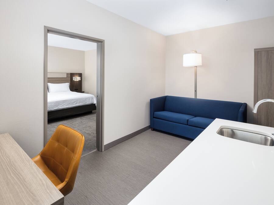 Una habitación de hotel con una cama, un sofá azul, un escritorio con una silla y un lavamanos.