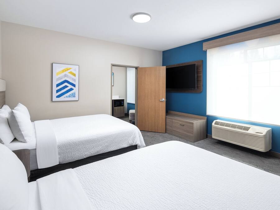 Camera d'albergo con due letti, una televisione a schermo piatto, un'ampia finestra e un condizionatore d'aria a parete.