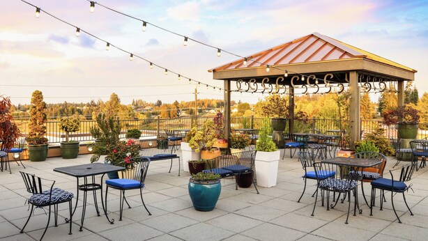 An outdoor patio with tables and chairs, a gazebo, and string lights.