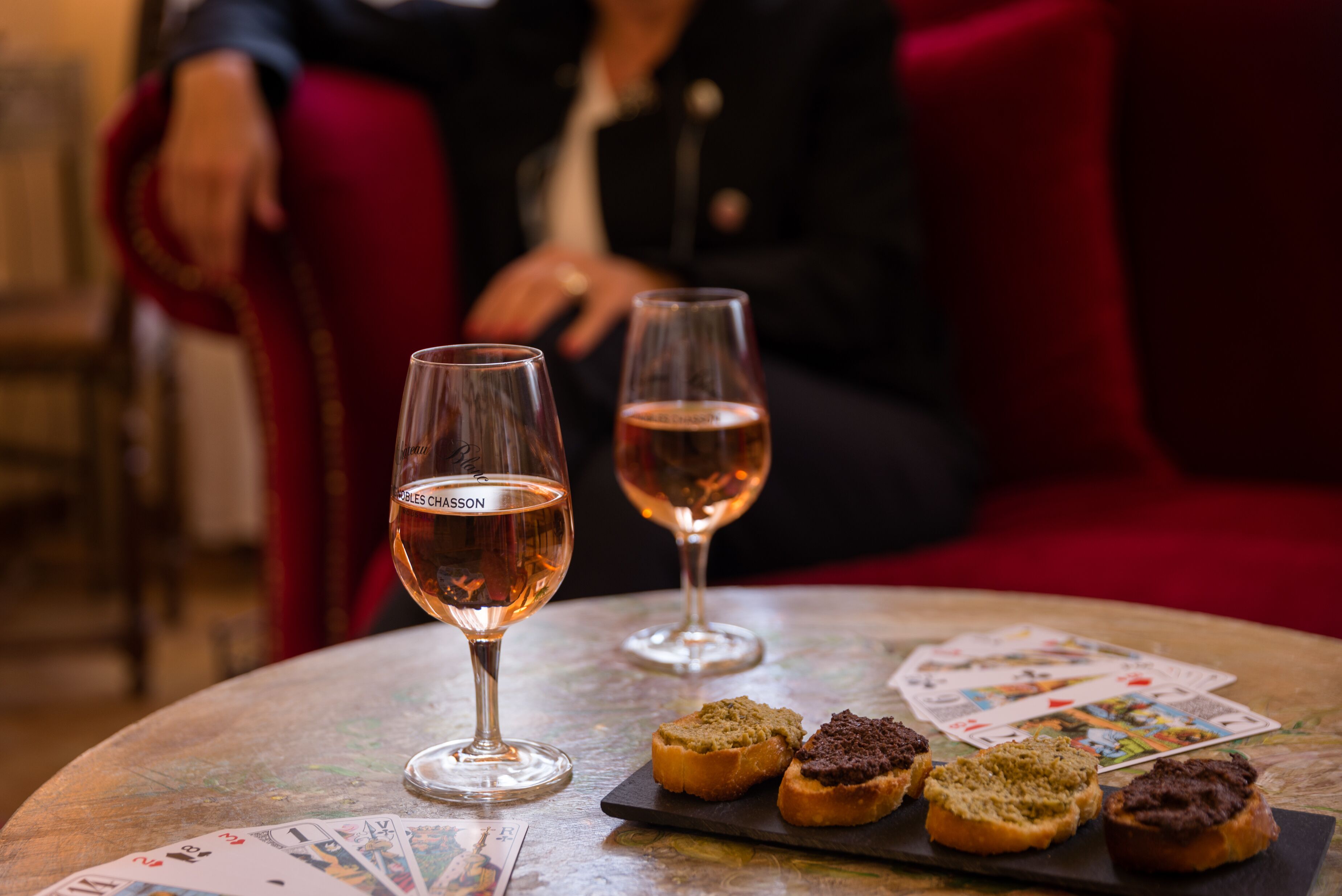 A table with two wine glasses, a deck of playing cards, and several small pastries.