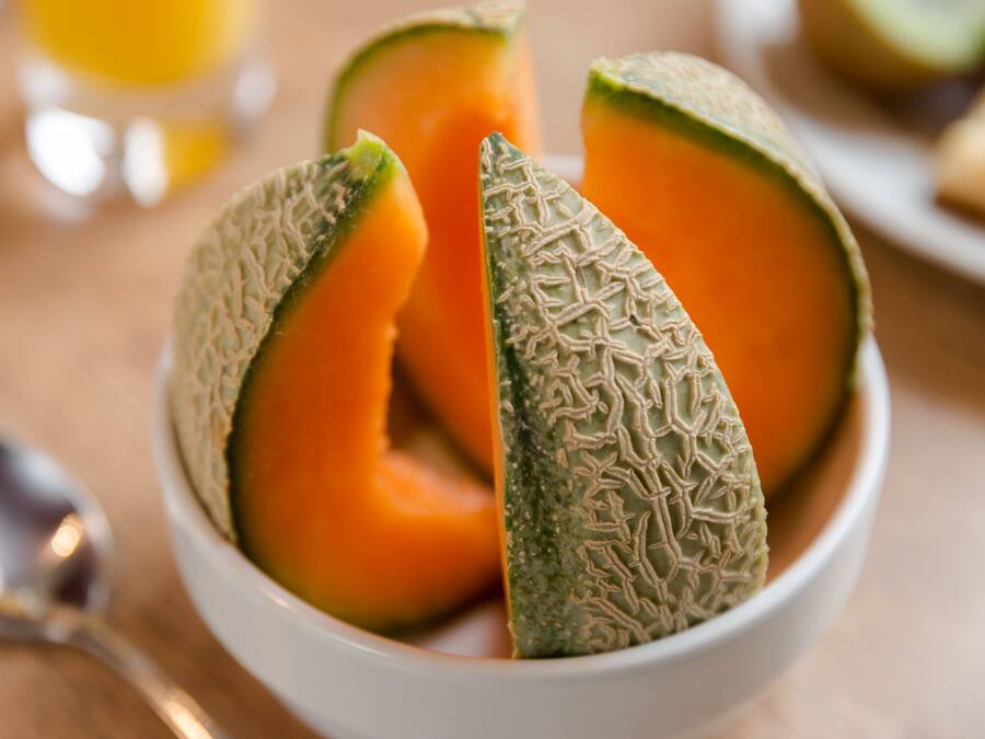 Un bol con mitades de melón cantalupo y piel rugosa.