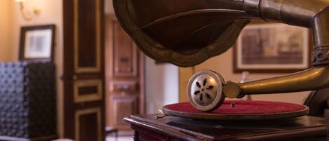 A vintage gramophone with a red mat, a wooden cabinet, and a framed picture on the wall.