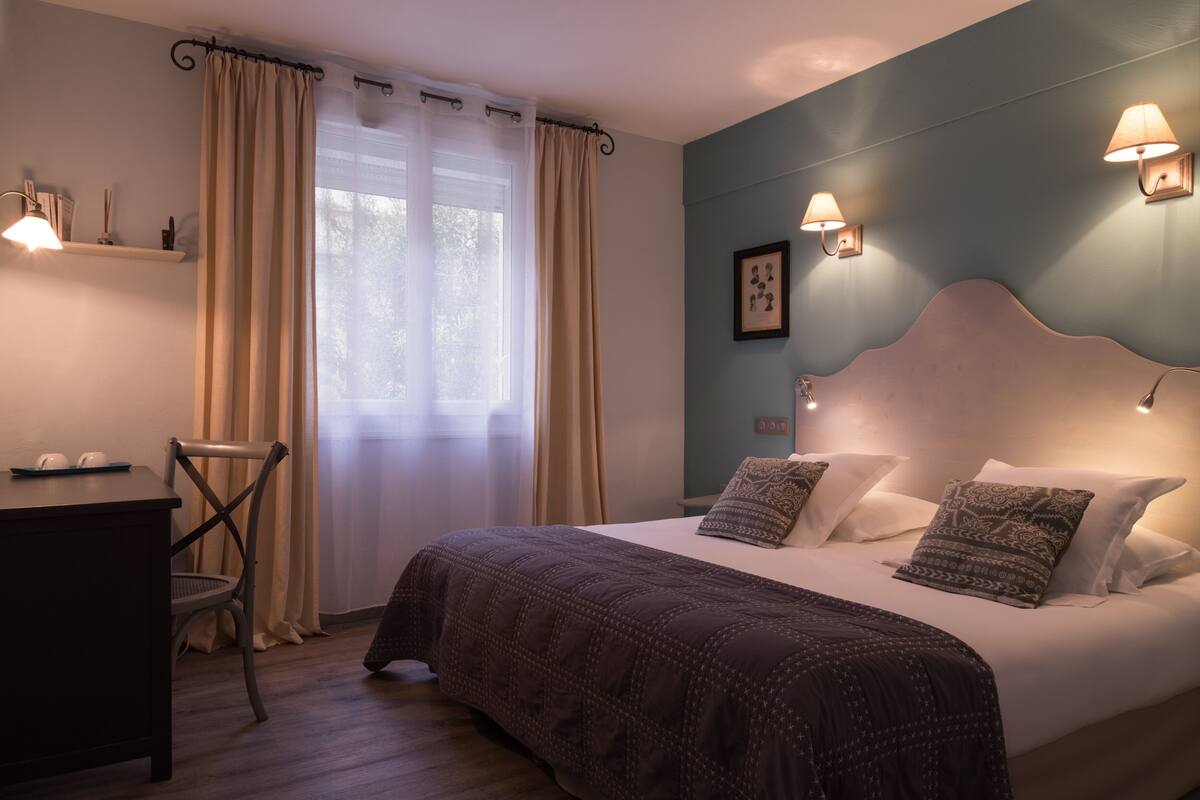 A bedroom with a bed, a desk, and a chair.