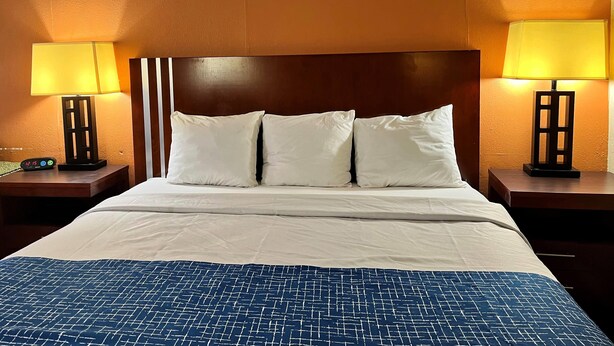 A hotel room with a large bed, two bedside tables, and two lamps. - Travelodge by Wyndham Seymour (Seymour)