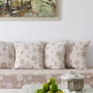 A room with a sofa and a table with a container and limes. - Folegandros Apartments (Folegandros)